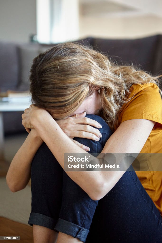 Sad woman resting head on knees at home